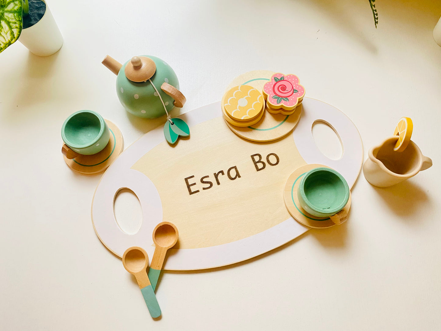 A wooden tea party set in green with cups, kettle, snacks and serving tray. Toy for kids 1 year or older.