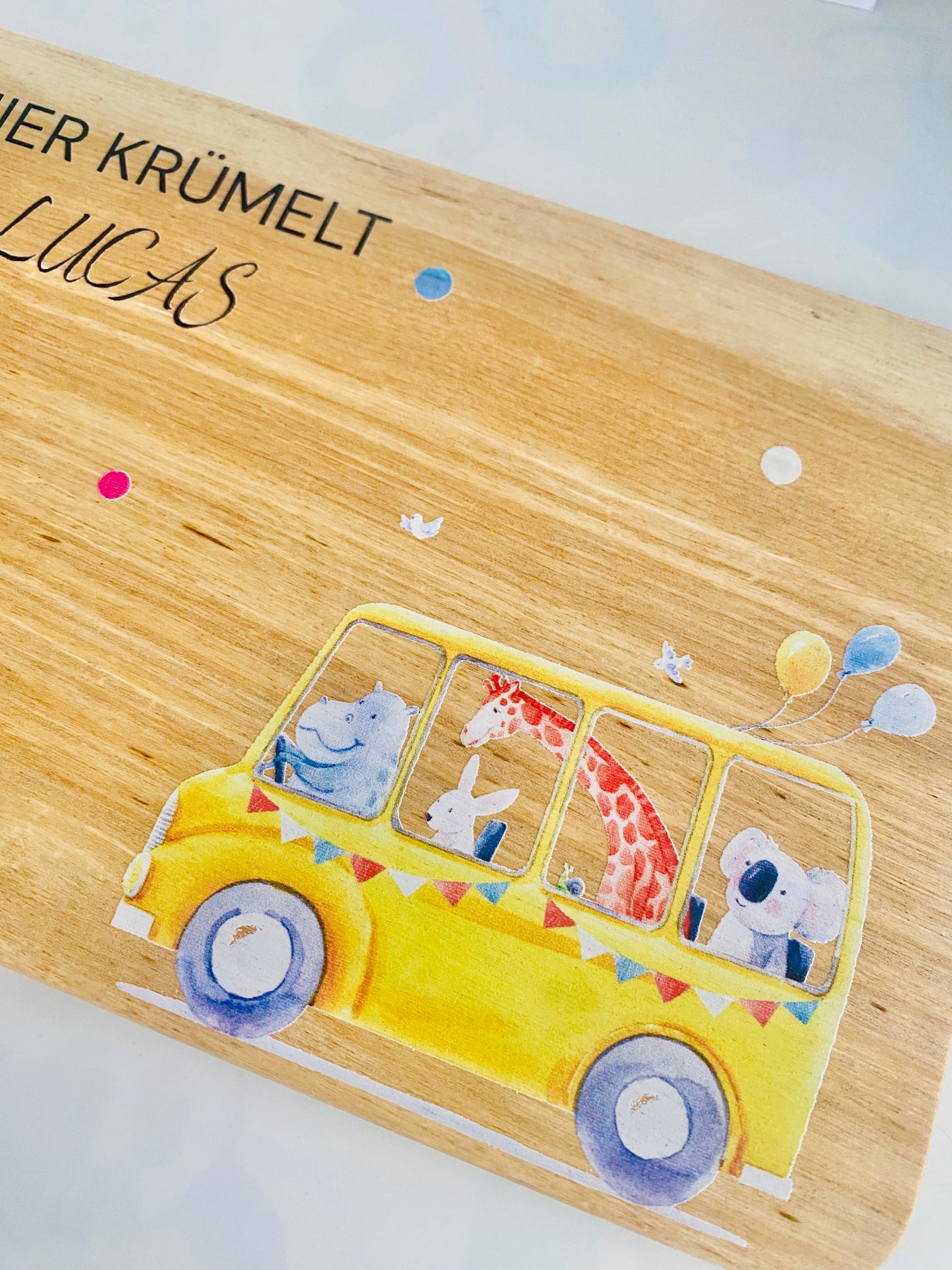 A close-up shot of breakfast board featuring animals in a yellow school bus. the bus is decorated with garlands.brotzeitbrett mit gravur