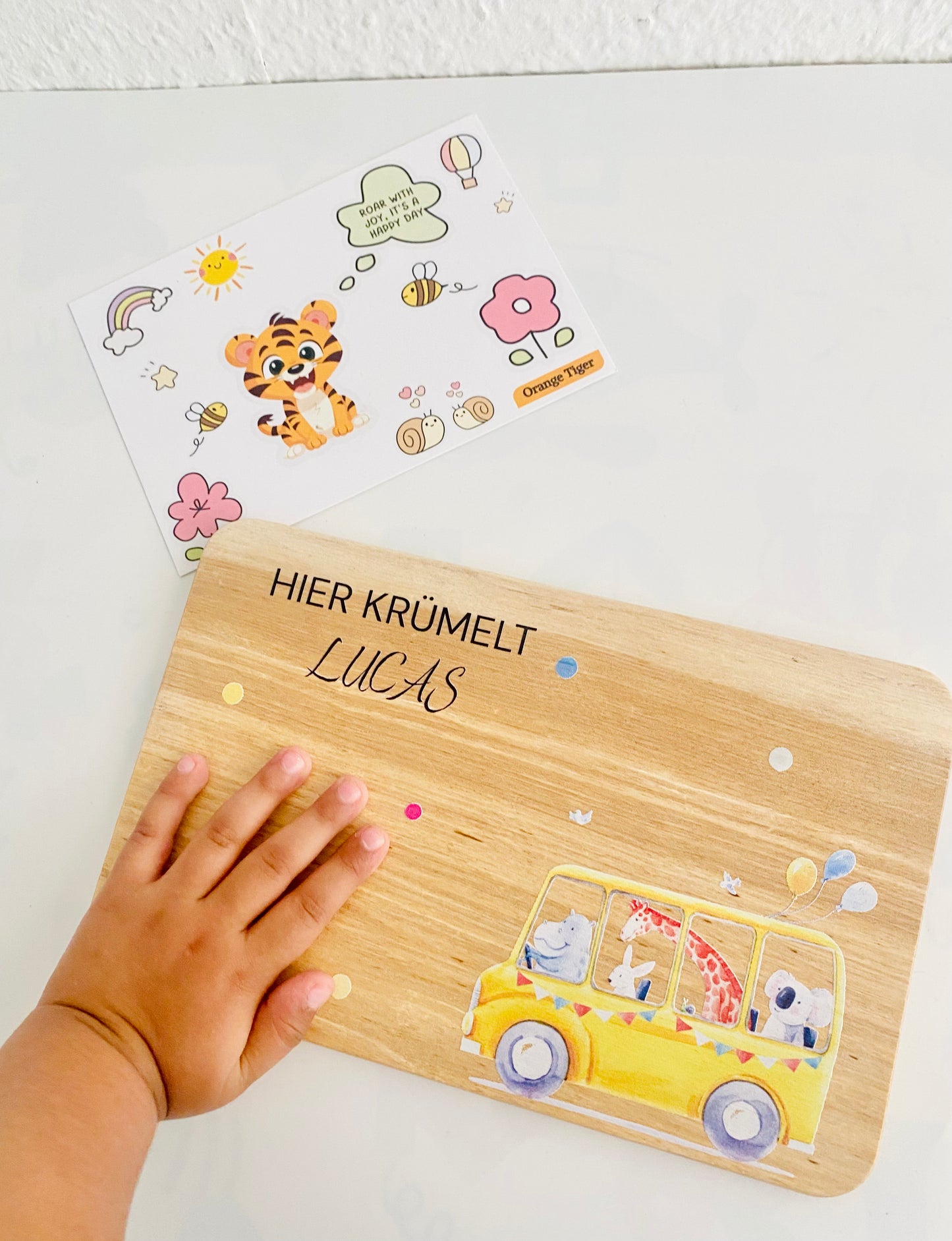 A child is touching the breakfast board which says" Here Crumble " with wheels on the bus theme. A unique birthday gift.